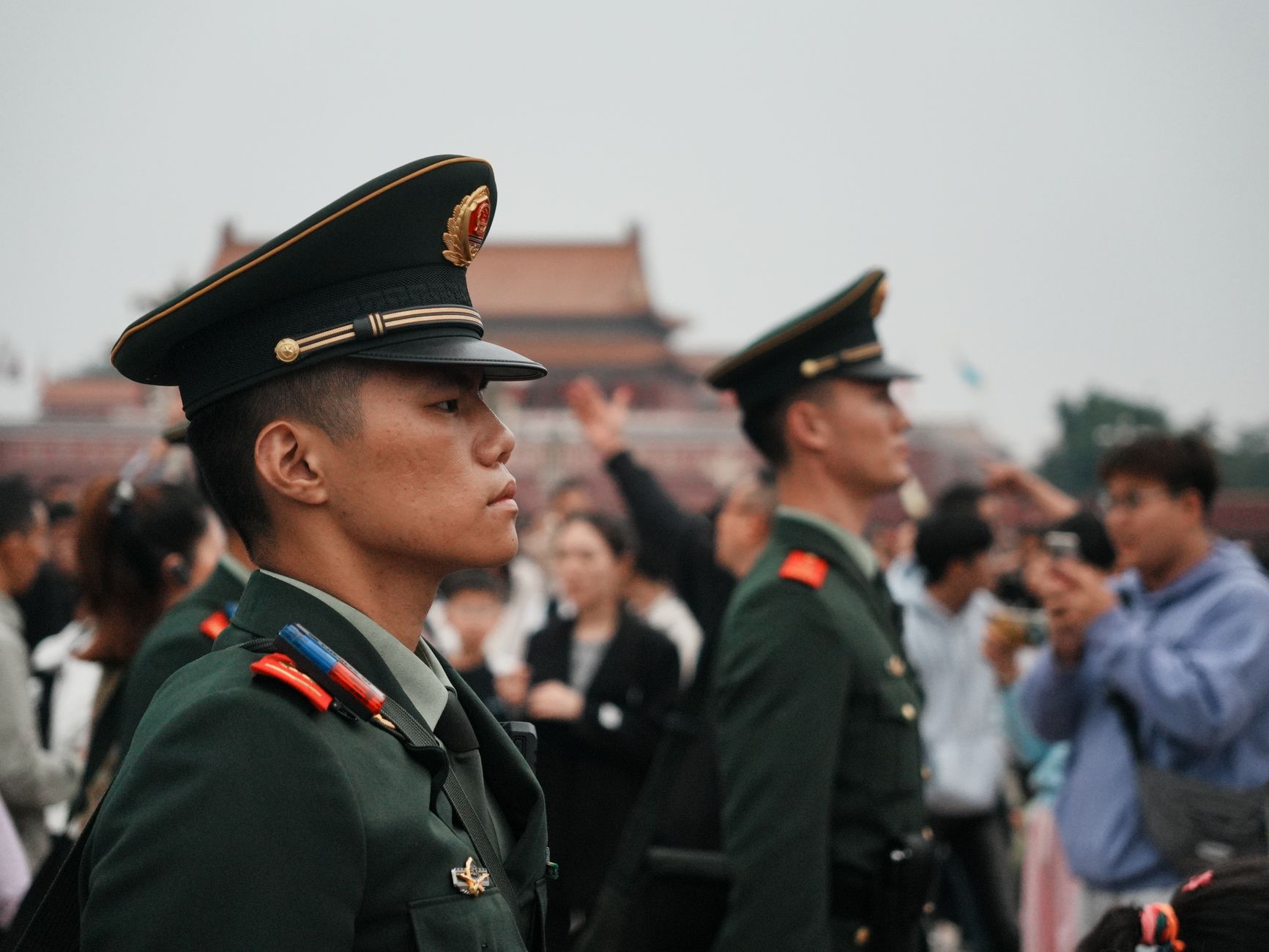 Uniformed guards stand vigil amidst a crowd at Tiananmen Square.