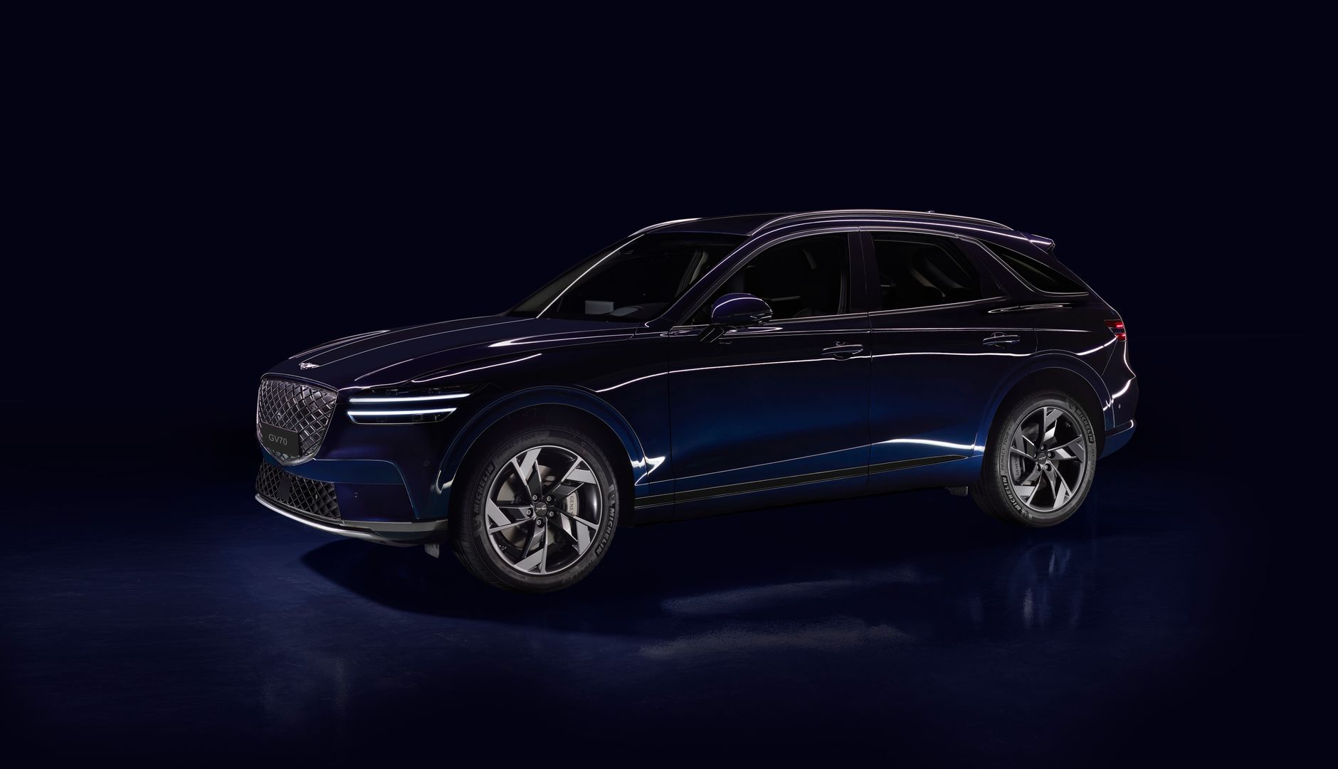 Stylish Genesis GV70 vehicle photographed in a studio with a blue livery and dark background.