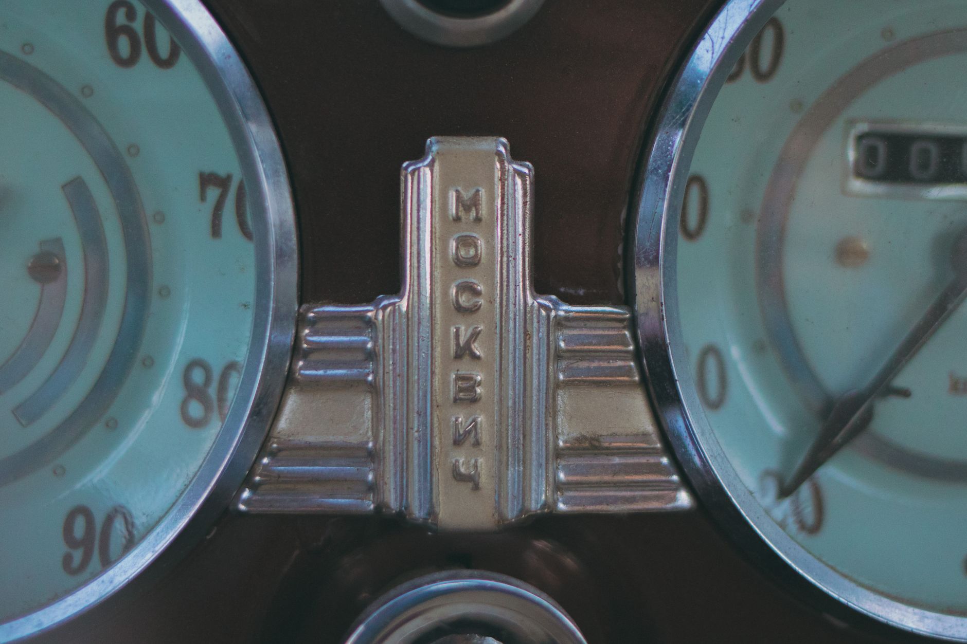 Close-up of an antique Moskvitch car speedometer with vintage design.