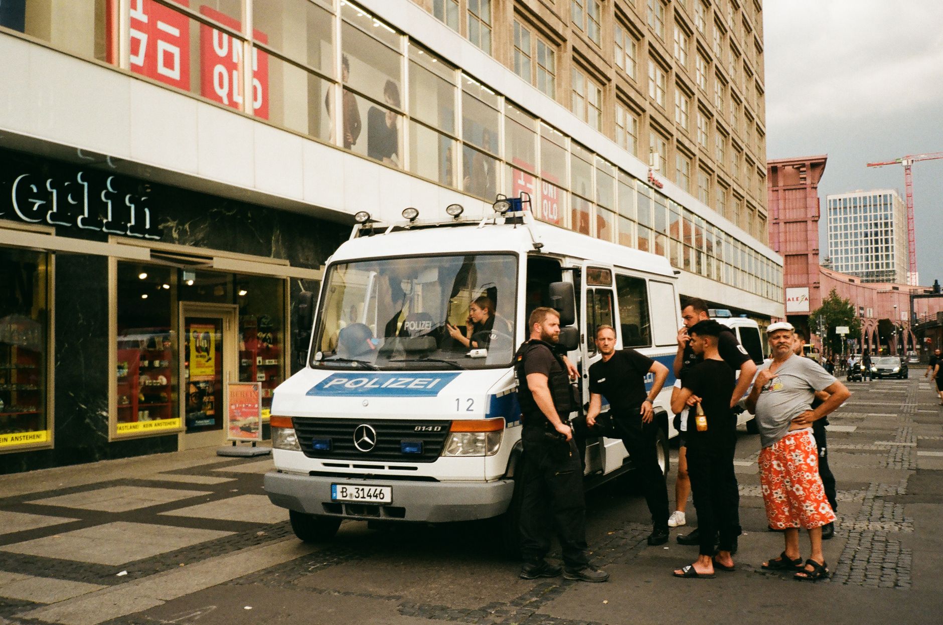Group of people interacting near a police van on city street, captured in an urban setting.