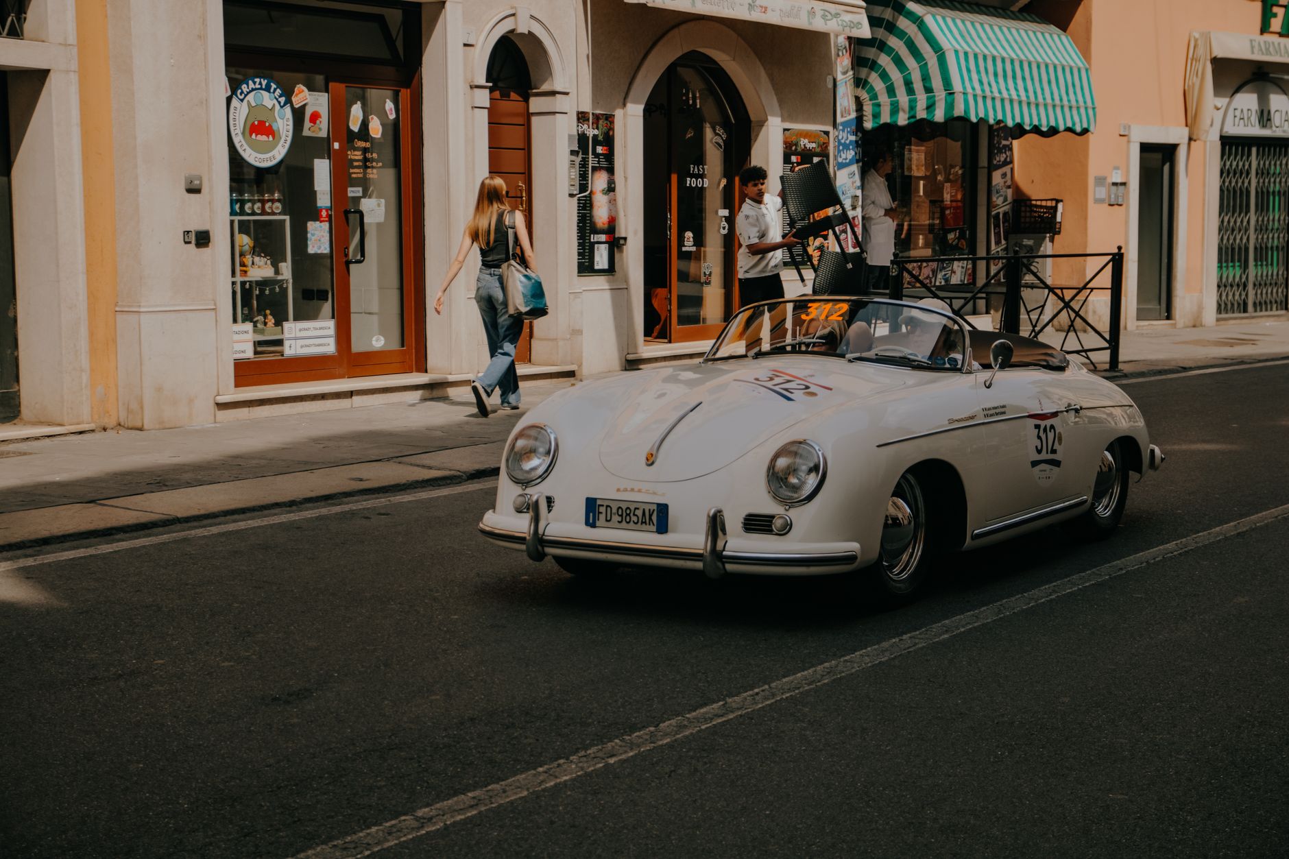 Classic vintage Porsche drives through Brescia, Italy, capturing the essence of retro automotive style.