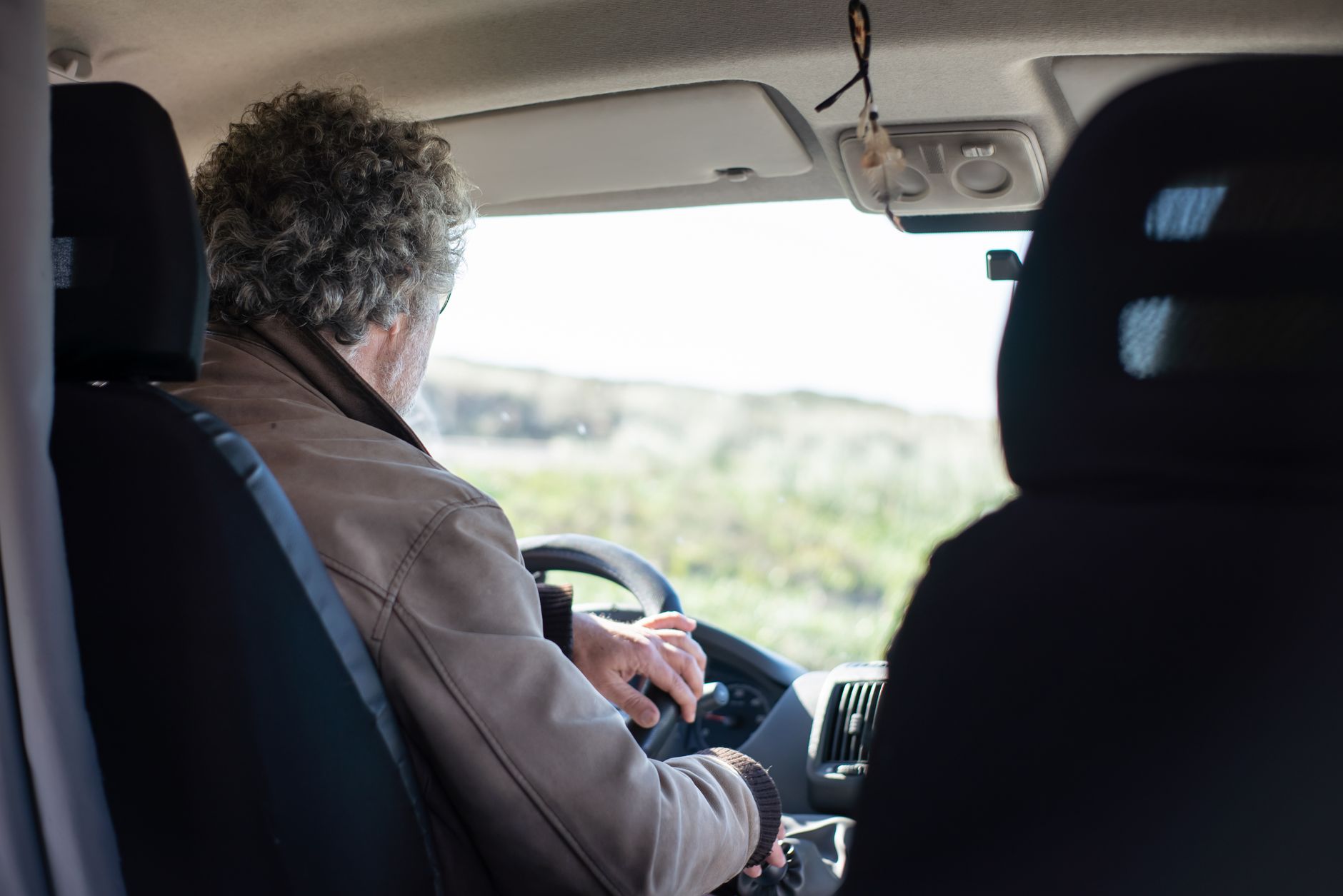 A senior man drives a motorhome through picturesque Portuguese countryside, highlighting travel and adventure.