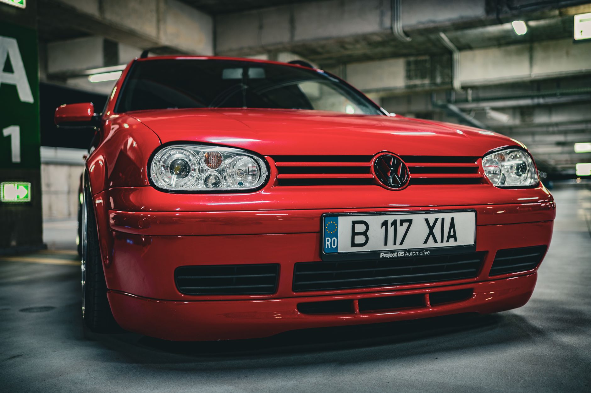 A red Volkswagen car parked in an indoor garage, showcasing its design and style.