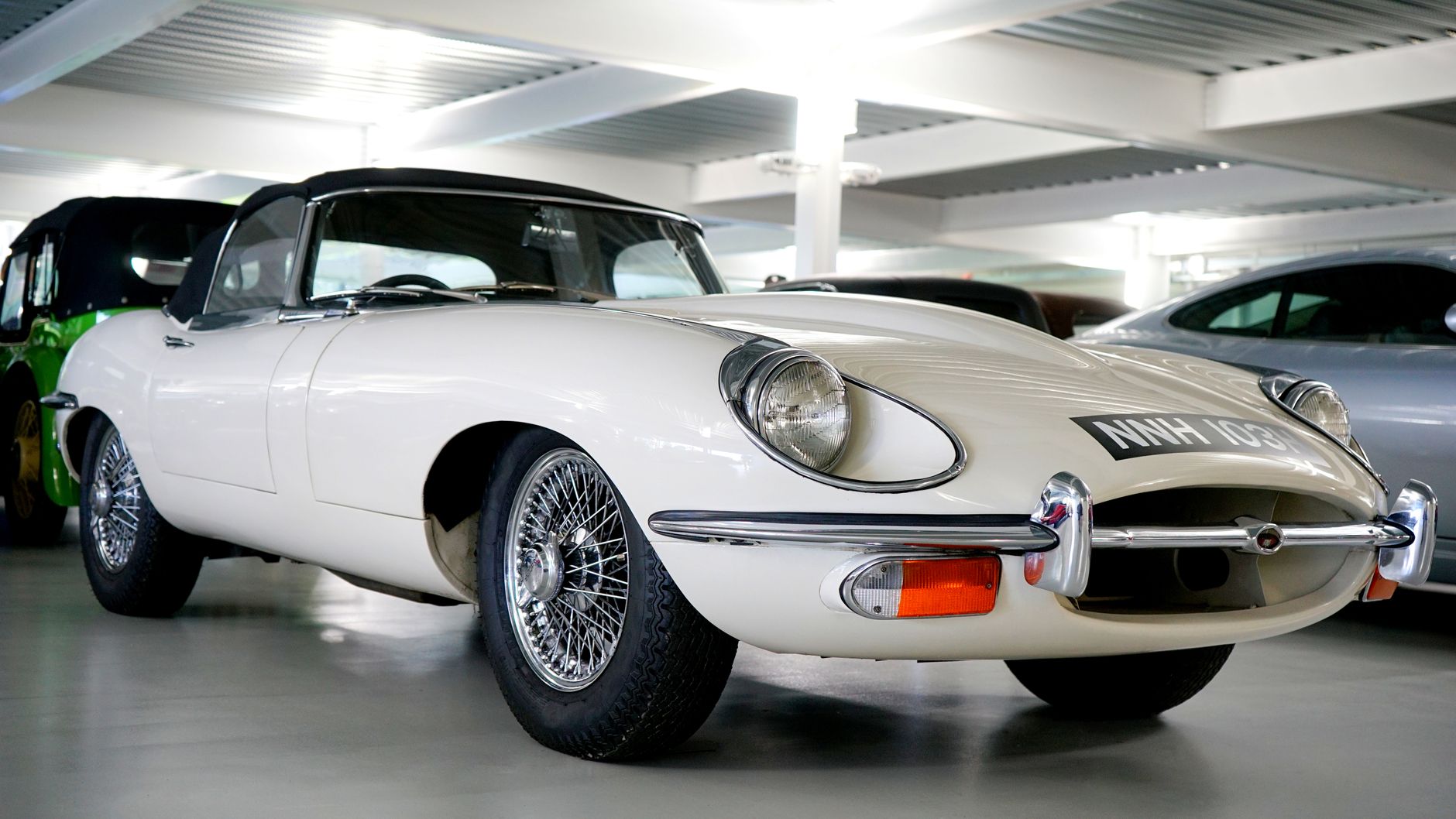 Vintage Jaguar E-Type coupe displayed in an indoor parking garage, showcasing classic automotive design.