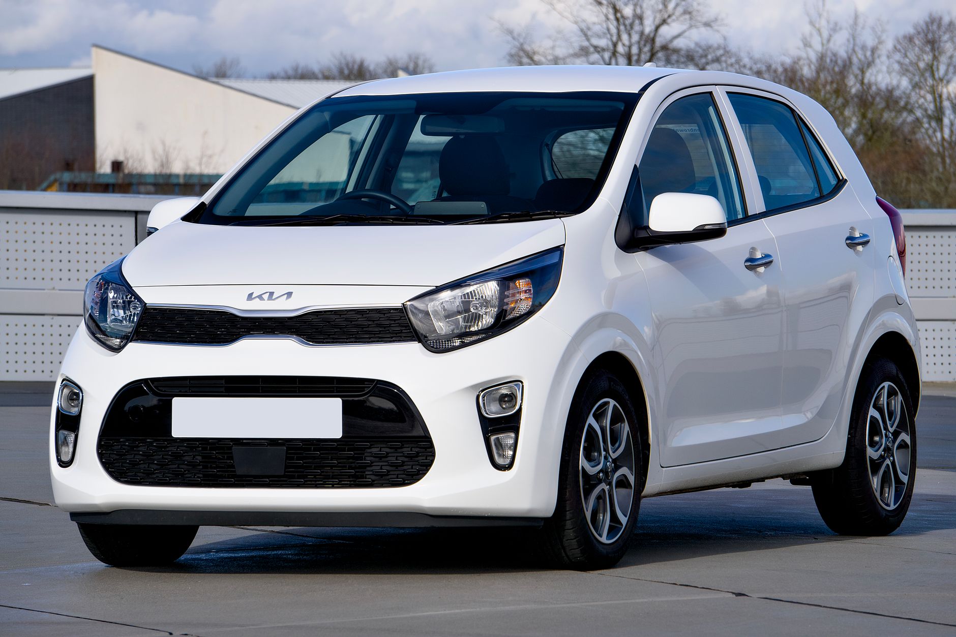 A pristine white Kia Picanto parked in an urban setting in Harlow, United Kingdom.