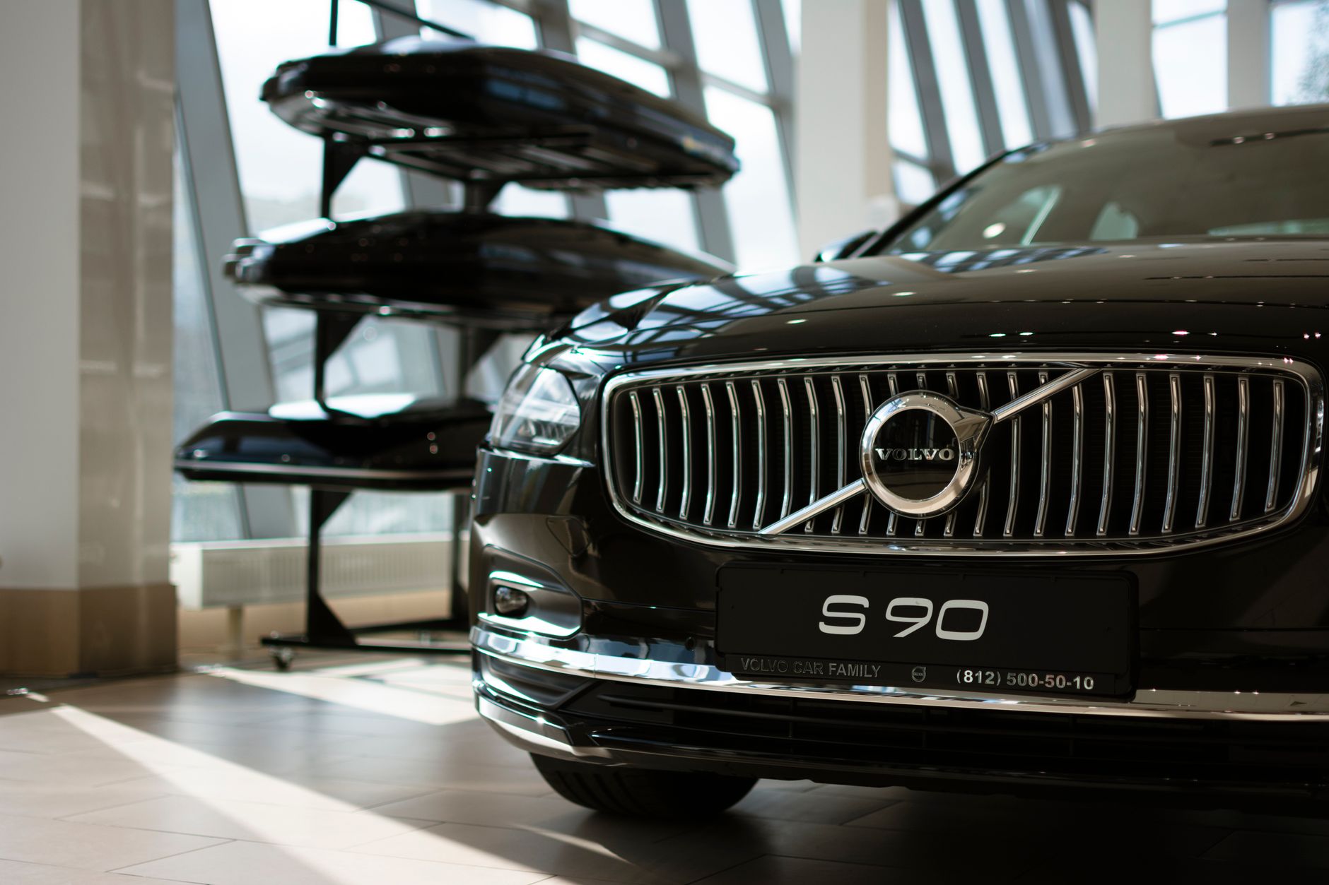 Black Volvo S90 displayed in a modern showroom, emphasizing luxury and elegance.