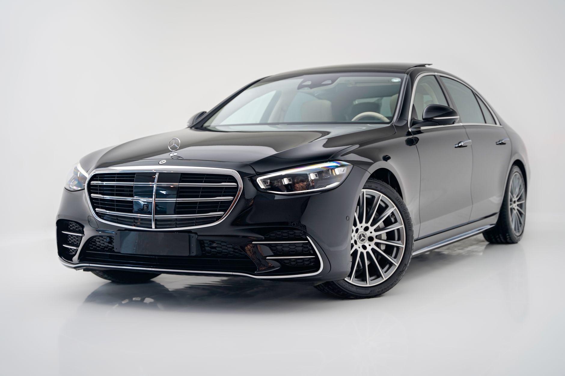 Capture of a sleek black luxury Mercedes-Benz S-Class sedan in a contemporary showroom.