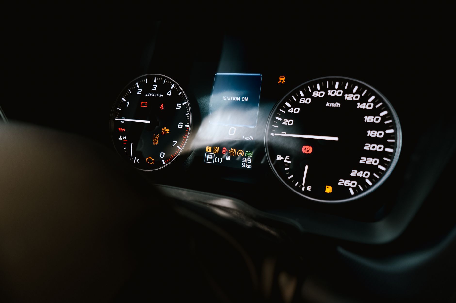 Detailed view of a car dashboard showing speedometer, tachometer, and warning lights, with ignition on.