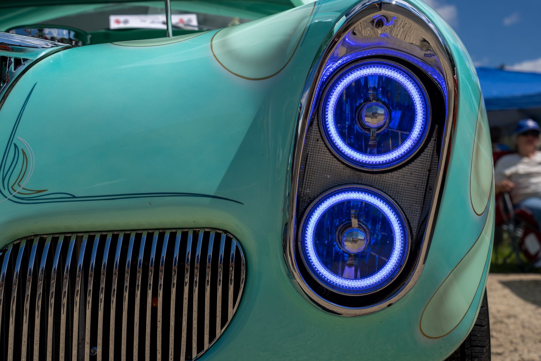 Detailed view of vintage car headlights with distinctive blue halos, outdoors, summer day in Nelson, Wisconsin.