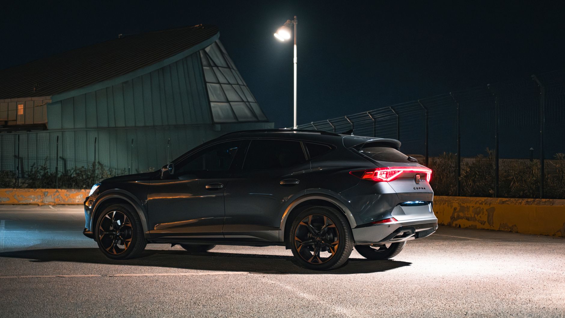 High angle view of a sleek modern SUV parked at night near an industrial building.