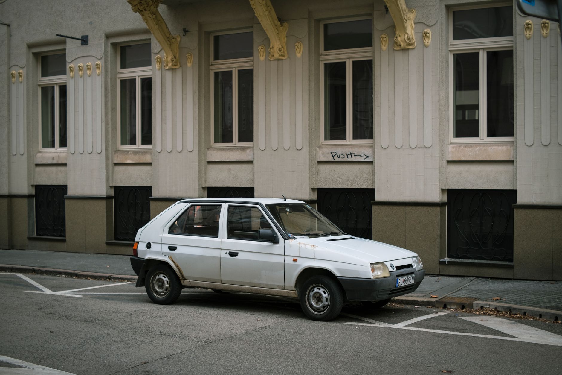 A classic white hatchback parked in an urban setting in Bratislava, Slovakia.