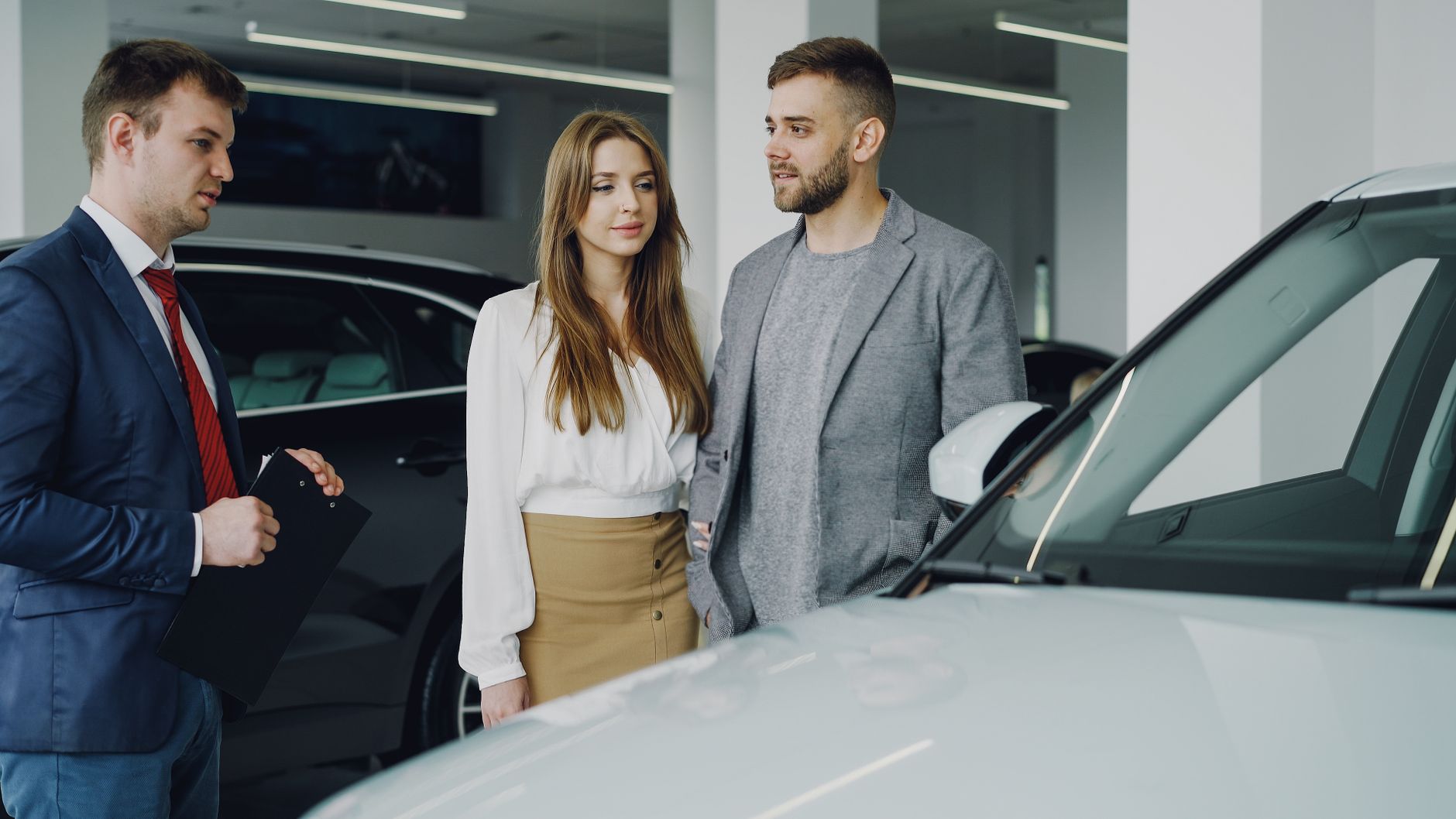 Couple discussing options with a car salesman inside a dealership.