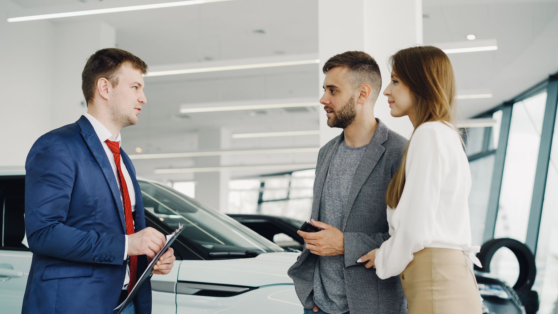Car salesman assisting a couple in a modern showroom with a luxury car.
