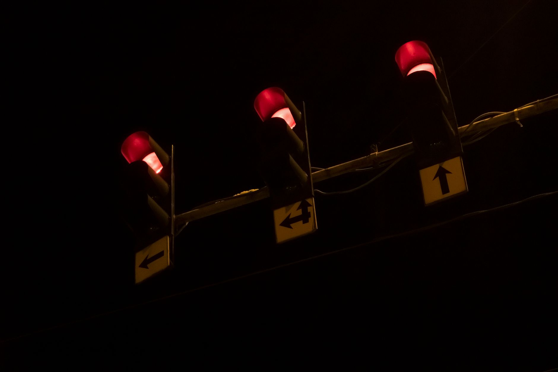 Three red traffic lights glowing brightly against a dark night sky, creating a vivid contrast.