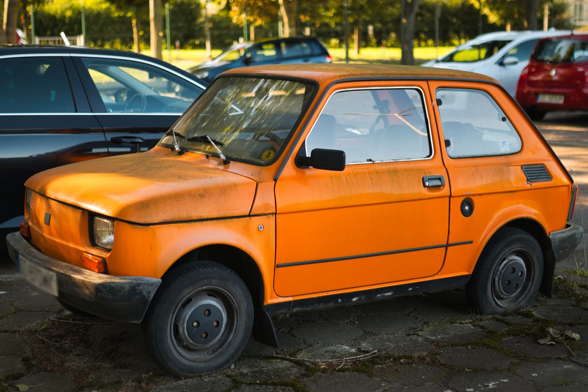 A classic orange Fiat 126 parked on a sunny day. Iconic vintage car with retro design.