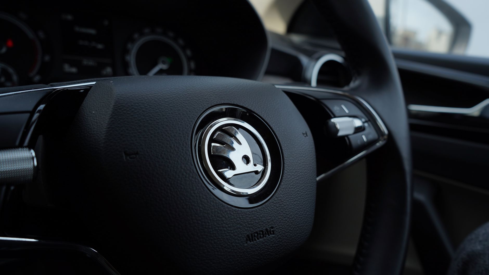 Detailed view of a Skoda steering wheel inside a vehicle, showcasing modern car design.