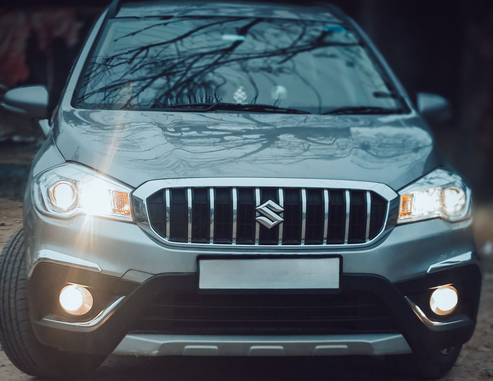 Close-up of the front view of a silver Suzuki SX4 S-Cross SUV highlighting its grill and headlights.