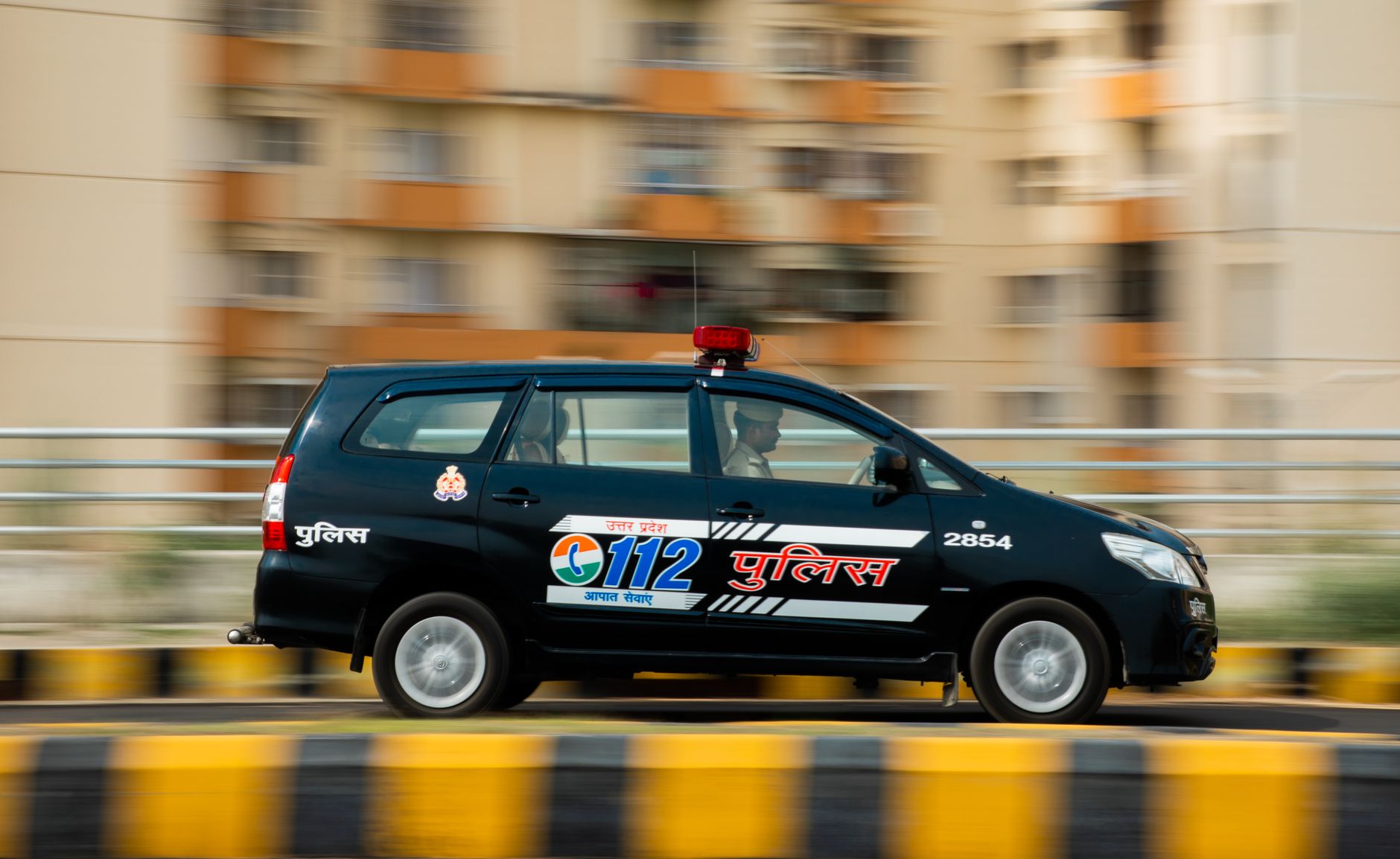 A police car speeds through a city street, showcasing urban emergency response.