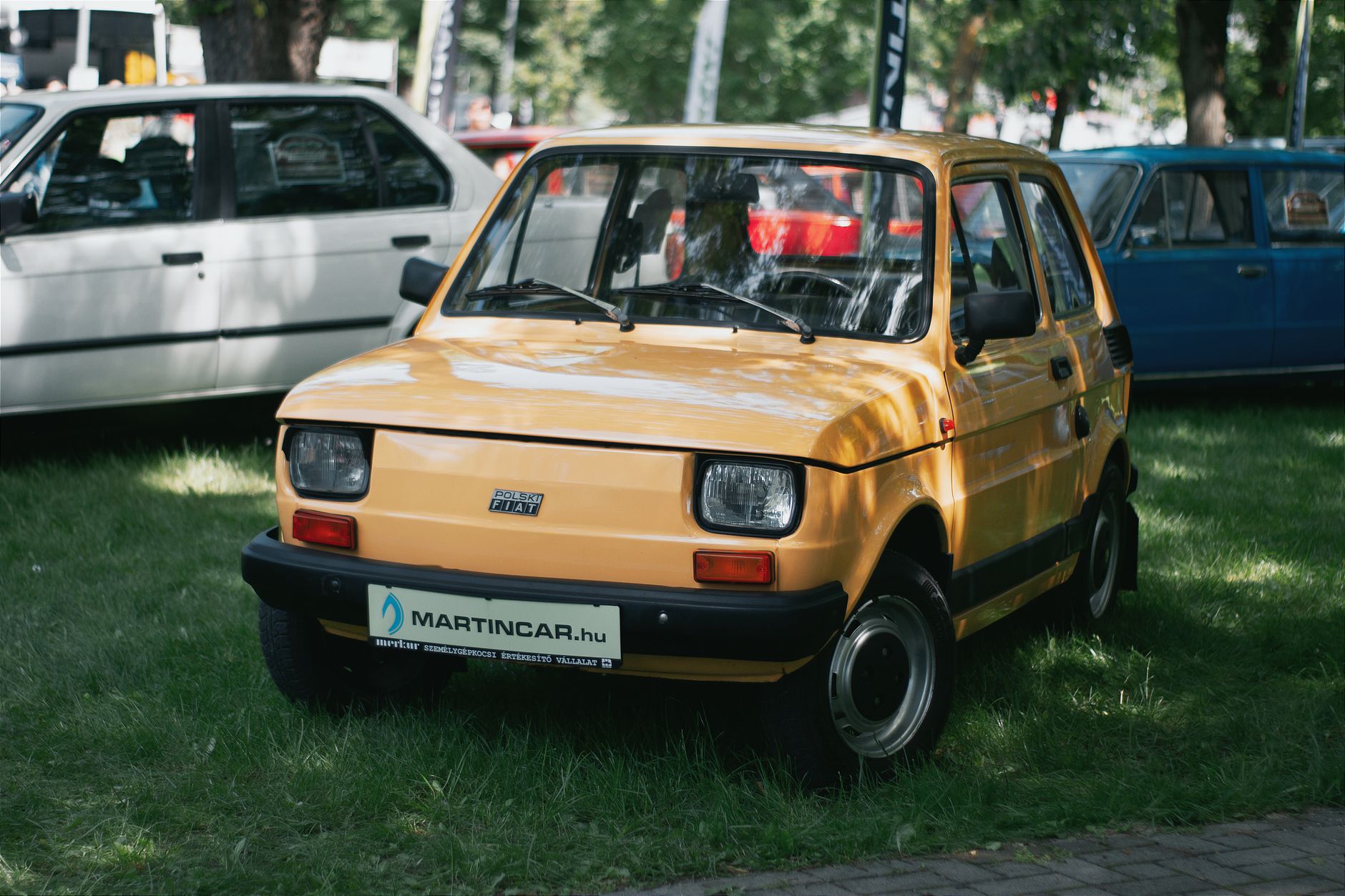 A vintage yellow Polski Fiat showcased in an outdoor car exhibition in Hungary.