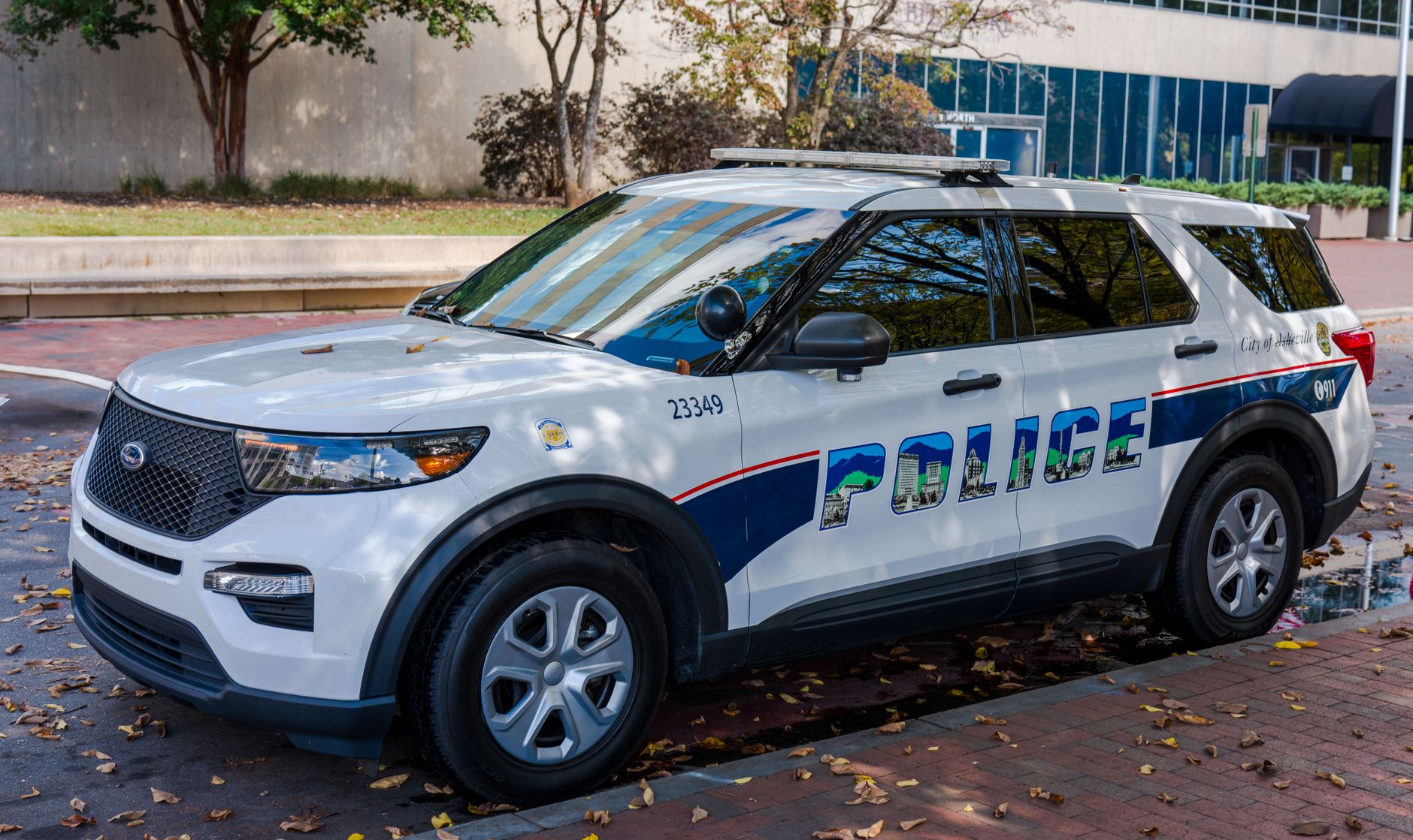 White police SUV parked in a city street during daylight, showing reflections on its windows.