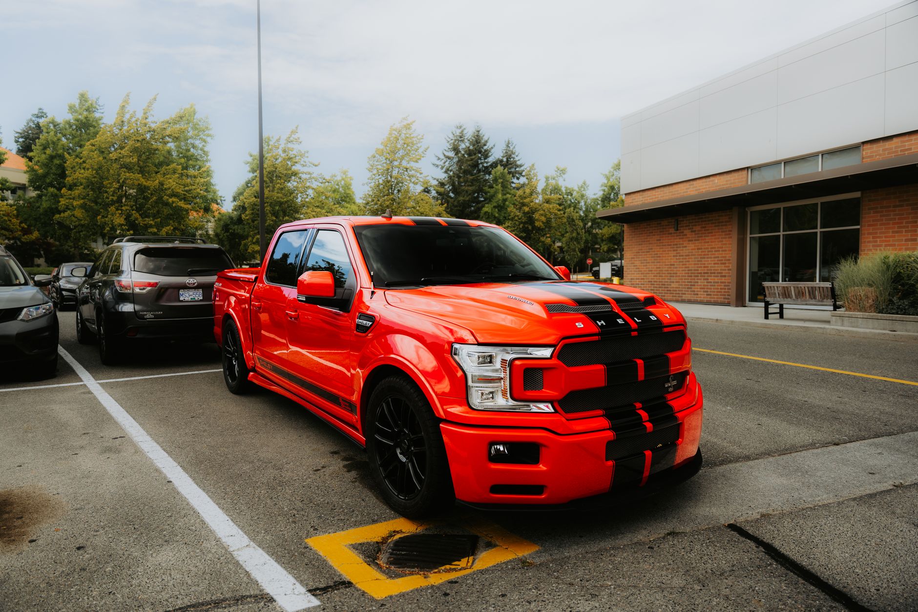 A striking red pickup truck parked outdoors on a sunny day in an urban setting.